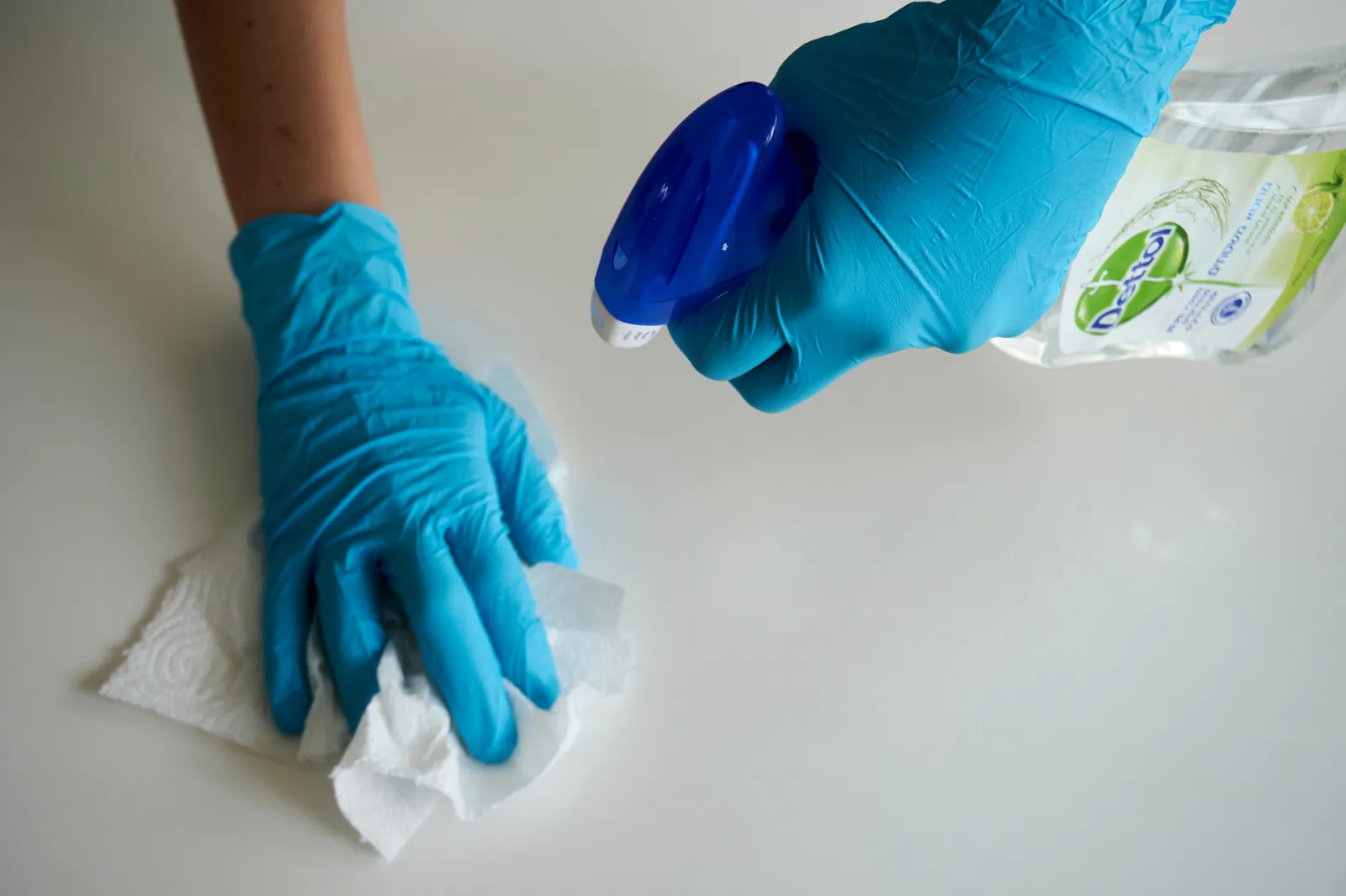 Cleaner in blue protective gloves cleaning a surface