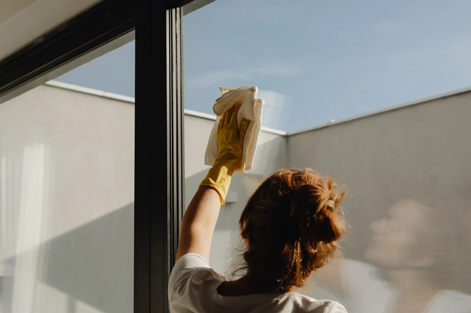 Cleaner wiping windows during a thorough deep clean